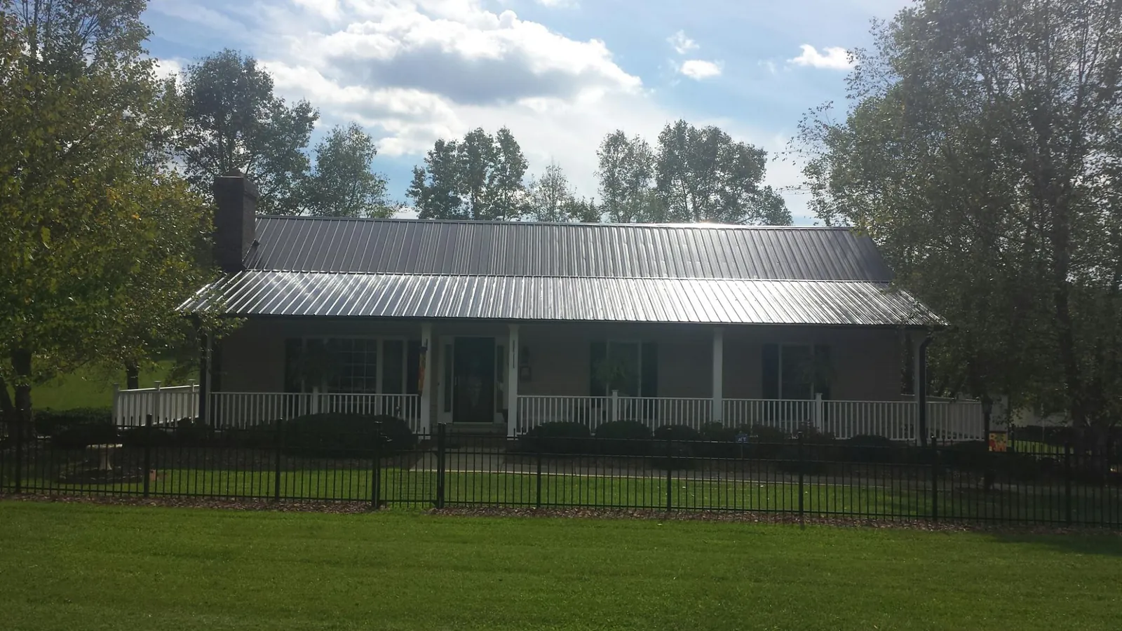 Gray metal roof on a brick ranch with a full width front porch — Gutter Guard Installation work by our crew in Plainfield